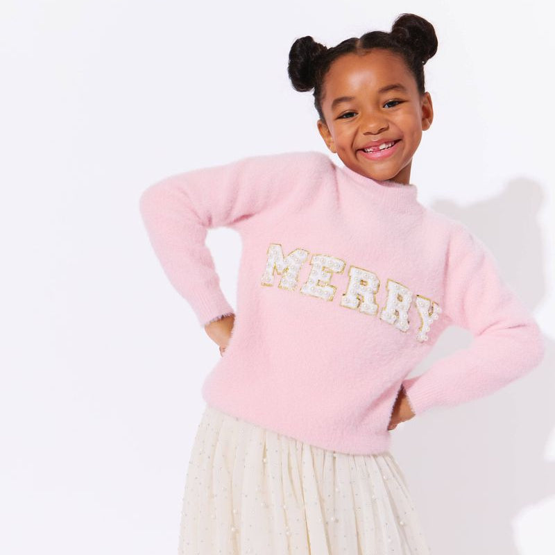Child wearing a pink sweater with 'Merry' text on a white background
