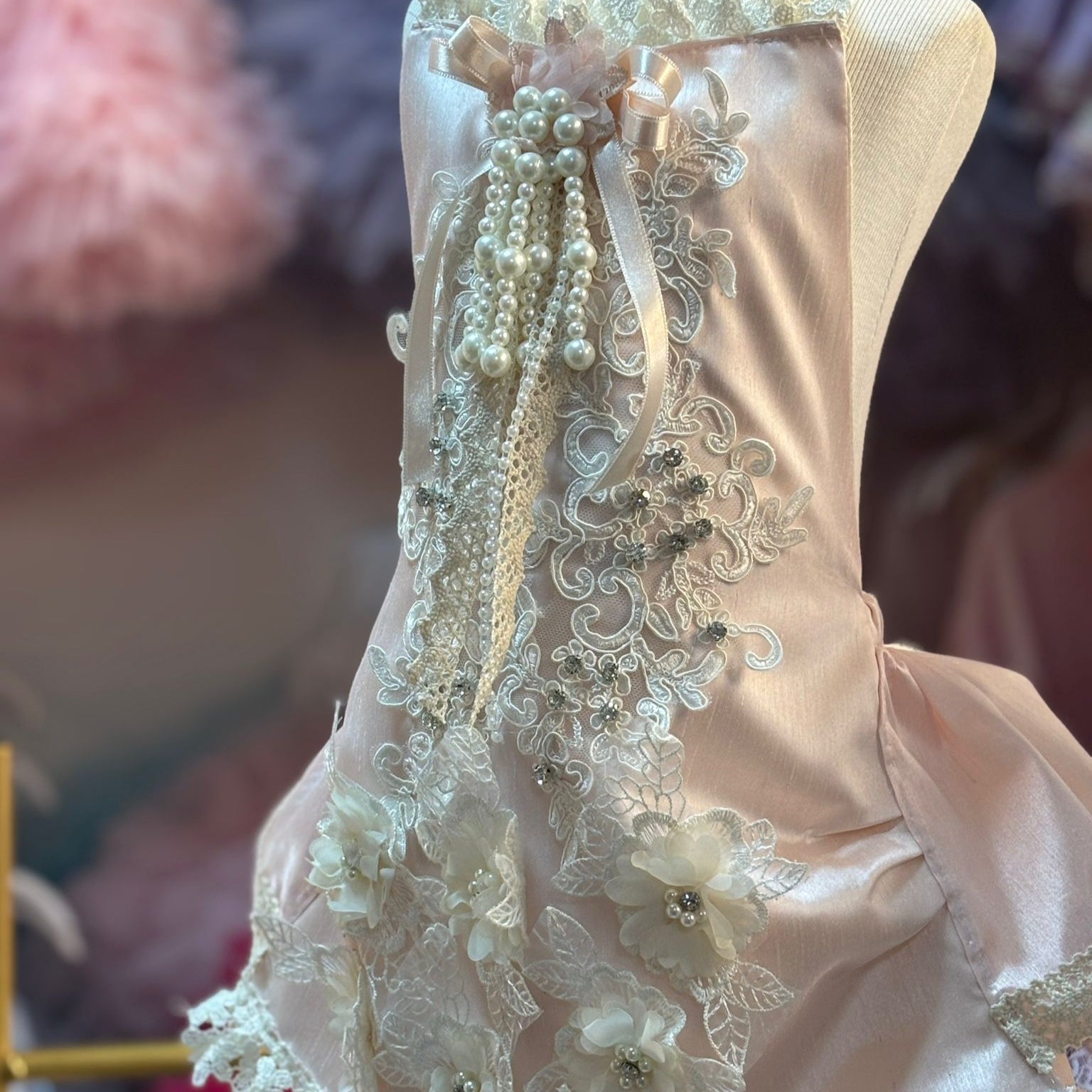 Delicate lace dress on a mannequin with floral embellishments.